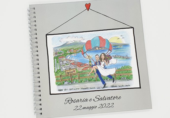 Guest book con rilegatura a spirale e stampa disegno caricatura fedele di sposi abbracciati che scendono con il paracadute. Nello sfondo il golfo di Napoli.