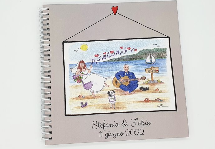 Guest book con rilegatura a spirale e stampa disegno caricatura fedele di sposi in spiaggia. La sposa seduta su una nota mentre lo sposo suona la chitarra, insieme a loro l'amico a 4 zampe che tiene il cuscino delle fedi.