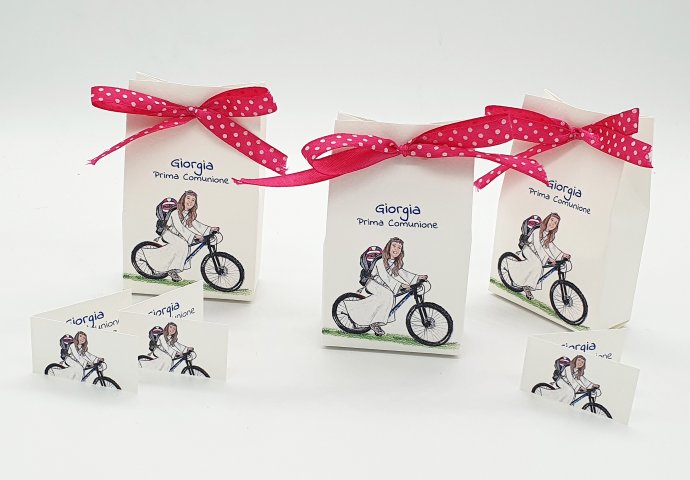 Scatolina porta confetti a sacchetto personalizzata con scenetta in stile caricatura fedele di bambina in montain bike con la tunica e lo zainetto sulle spalle con il suo pallone da pallavolo. Nello sfondo vista mare con Capri.